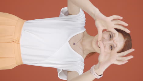 Vertical-video-of-Woman-making-heart-sign-at-camera.